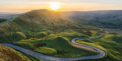 Sunset at Mam Tor in the Peak District with long winding road leading through valley